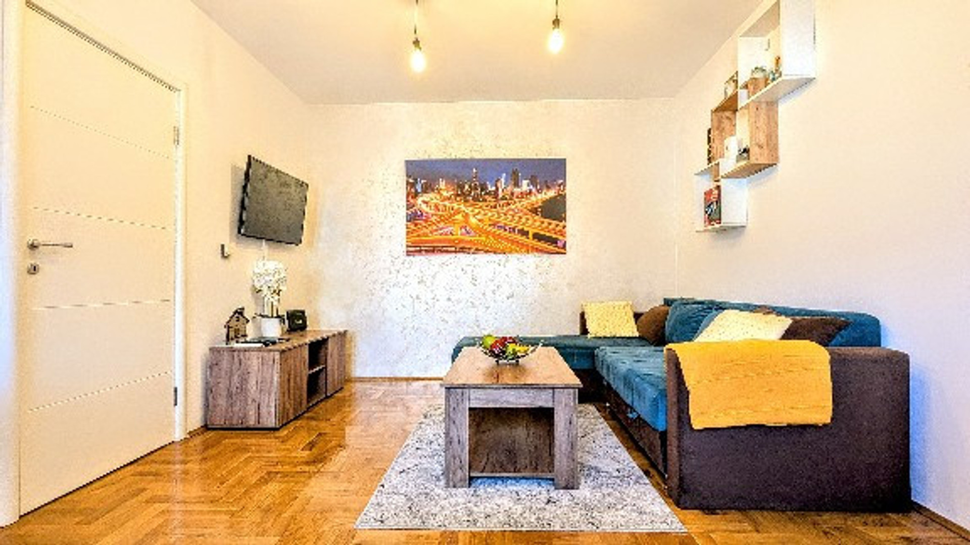 The living room is as spacious and bright as you can see in the picture. It is equipped with comfortable turquoise-green pull-out furniture, paintings, details that open up the space, a soft carpet, a table for storing things, a 35-inch plasma HD TV