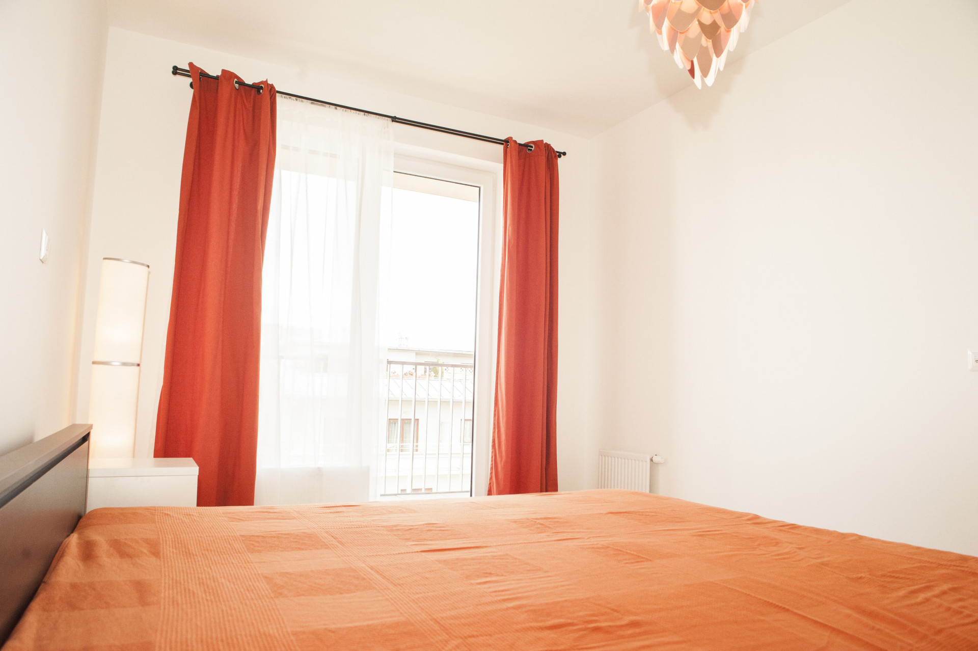 A bedroom with a king size bed and windows & entrance door to large terrace.