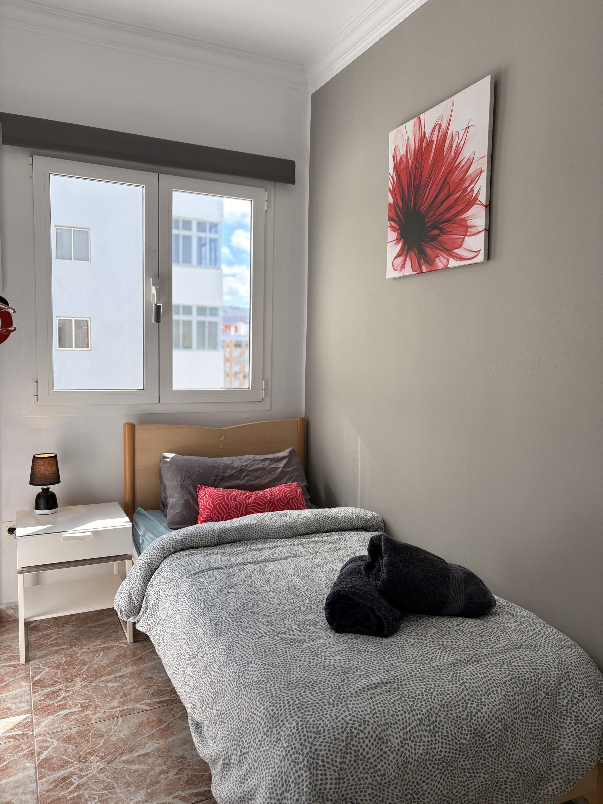 Single bed with red accent pillow