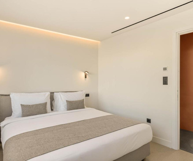 Bright bedroom with orange kitchen glimpse