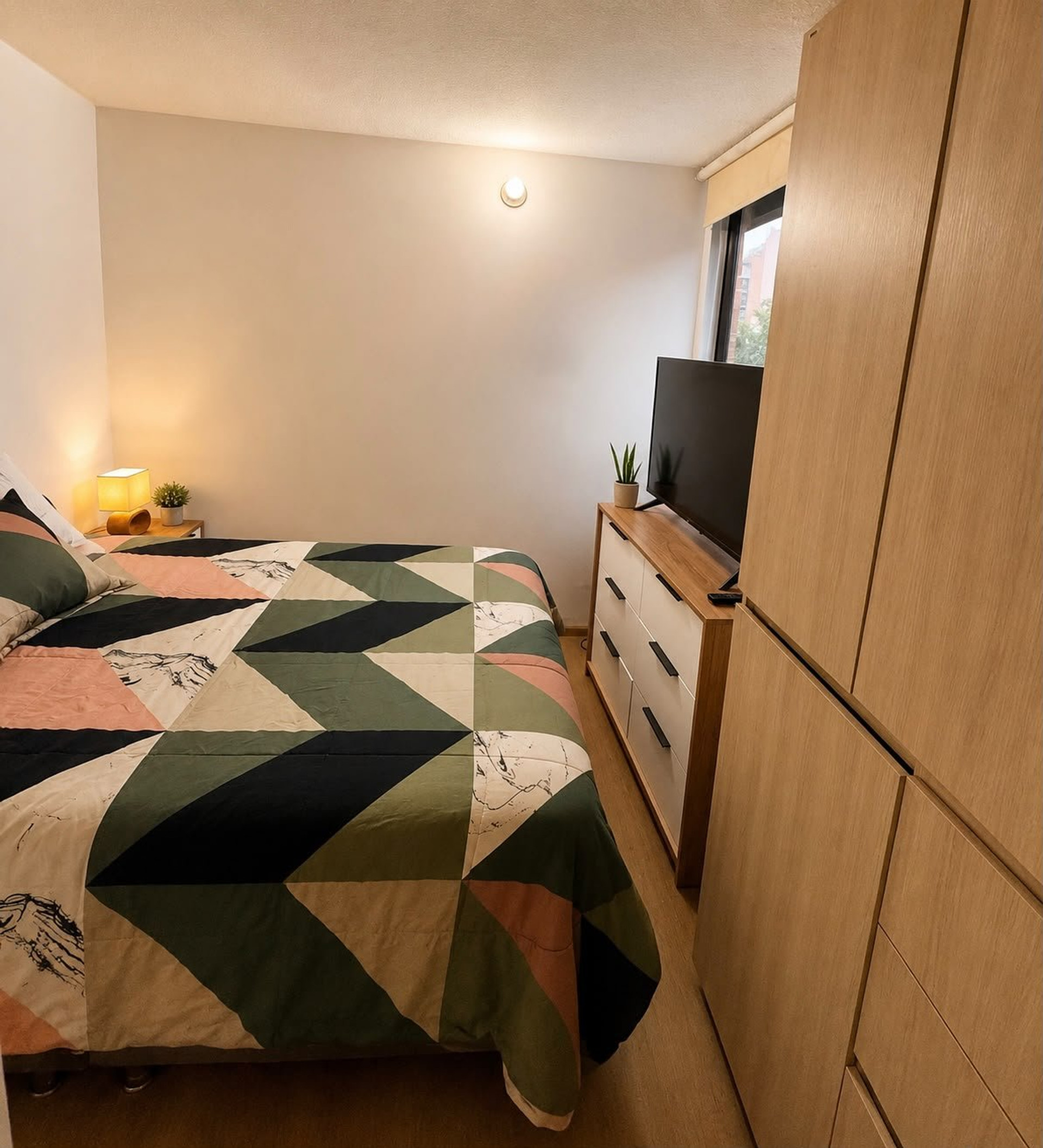 Bedroom with patterned bedspread and TV