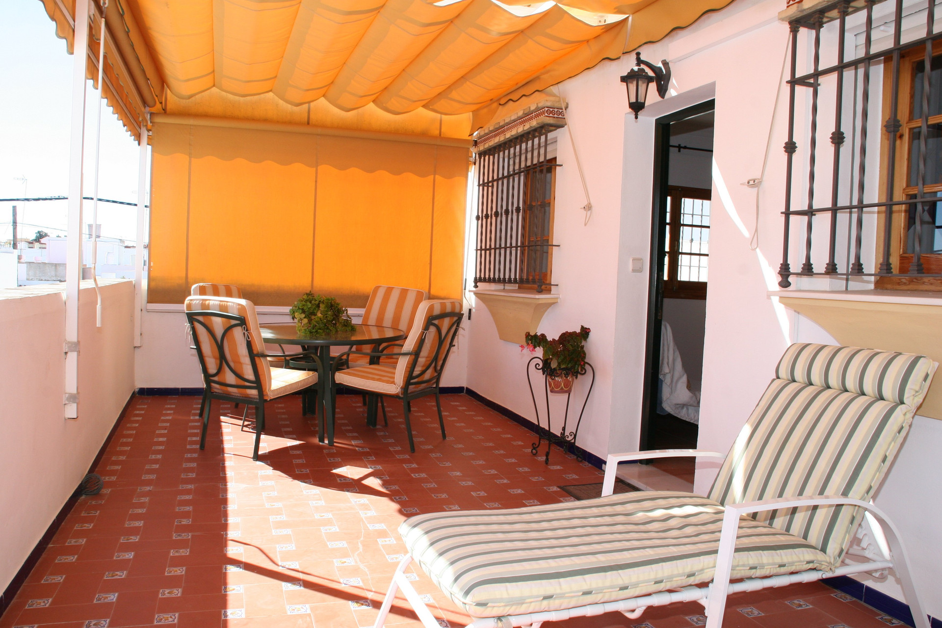 Covered terrace with dining table, loungers