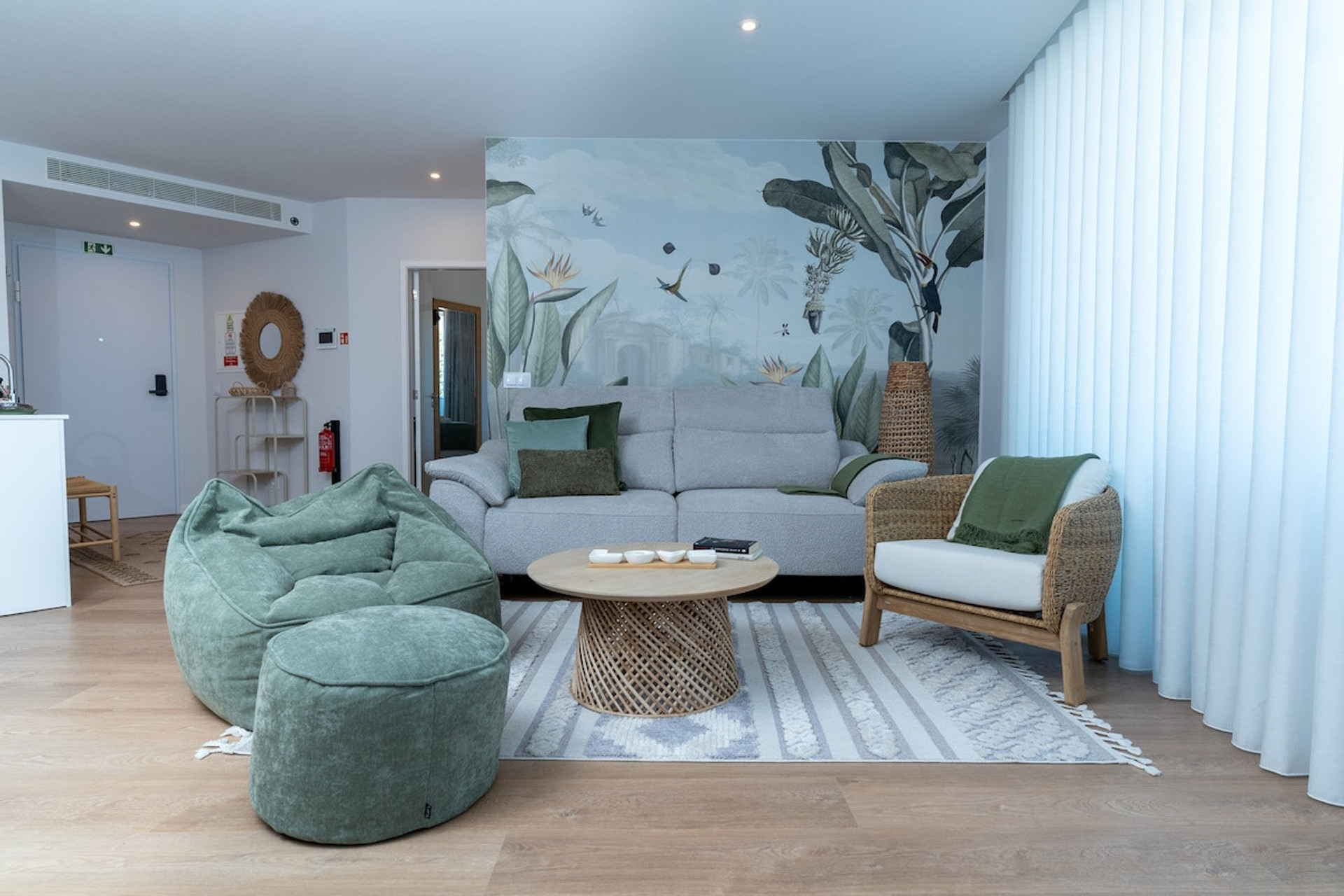 Elegant and cozy living room with green and natural tones, spacious sofa, ottoman and decorative wall that conveys comfort and harmony.