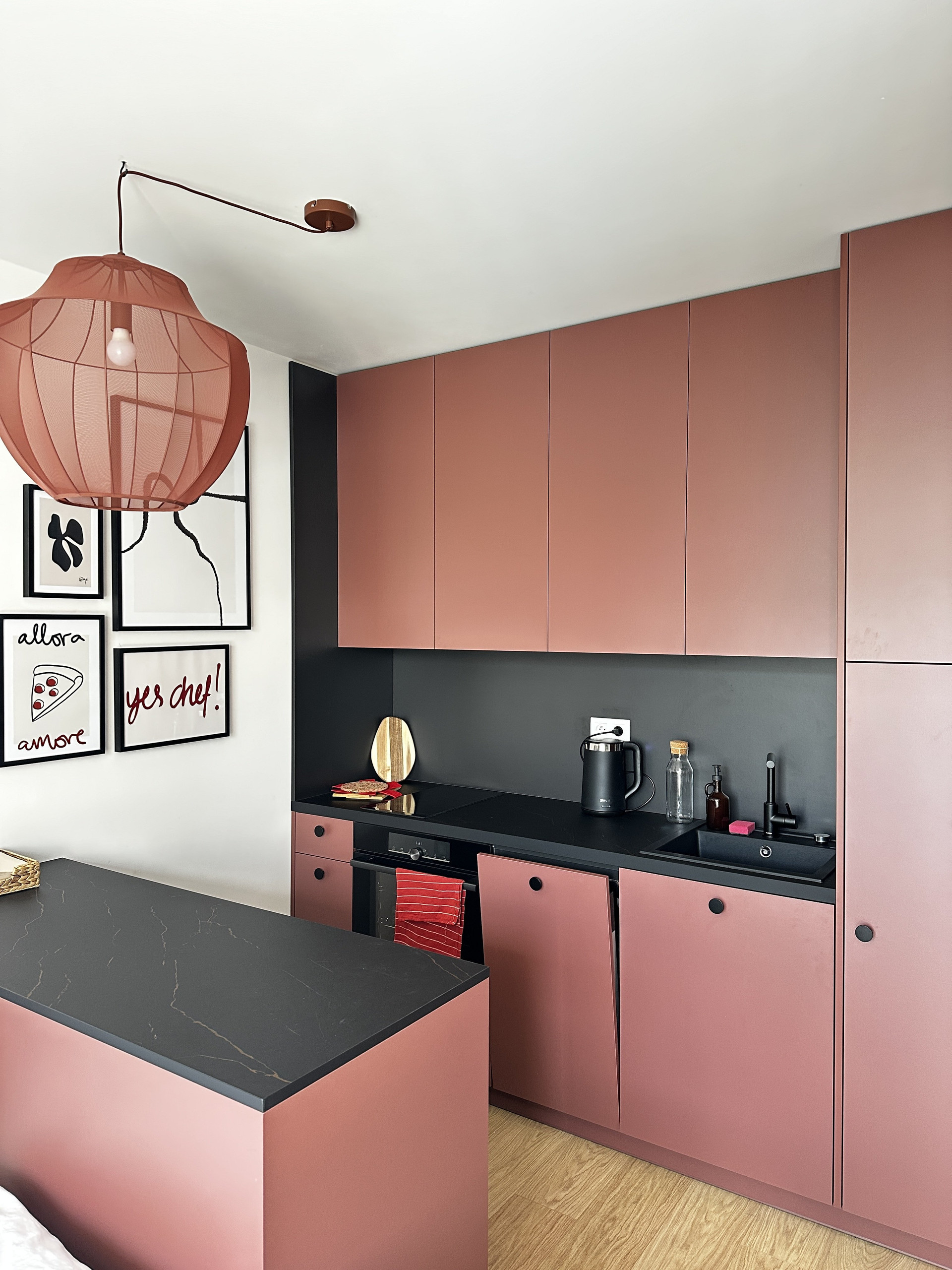 Pink kitchen cabinets with black countertop