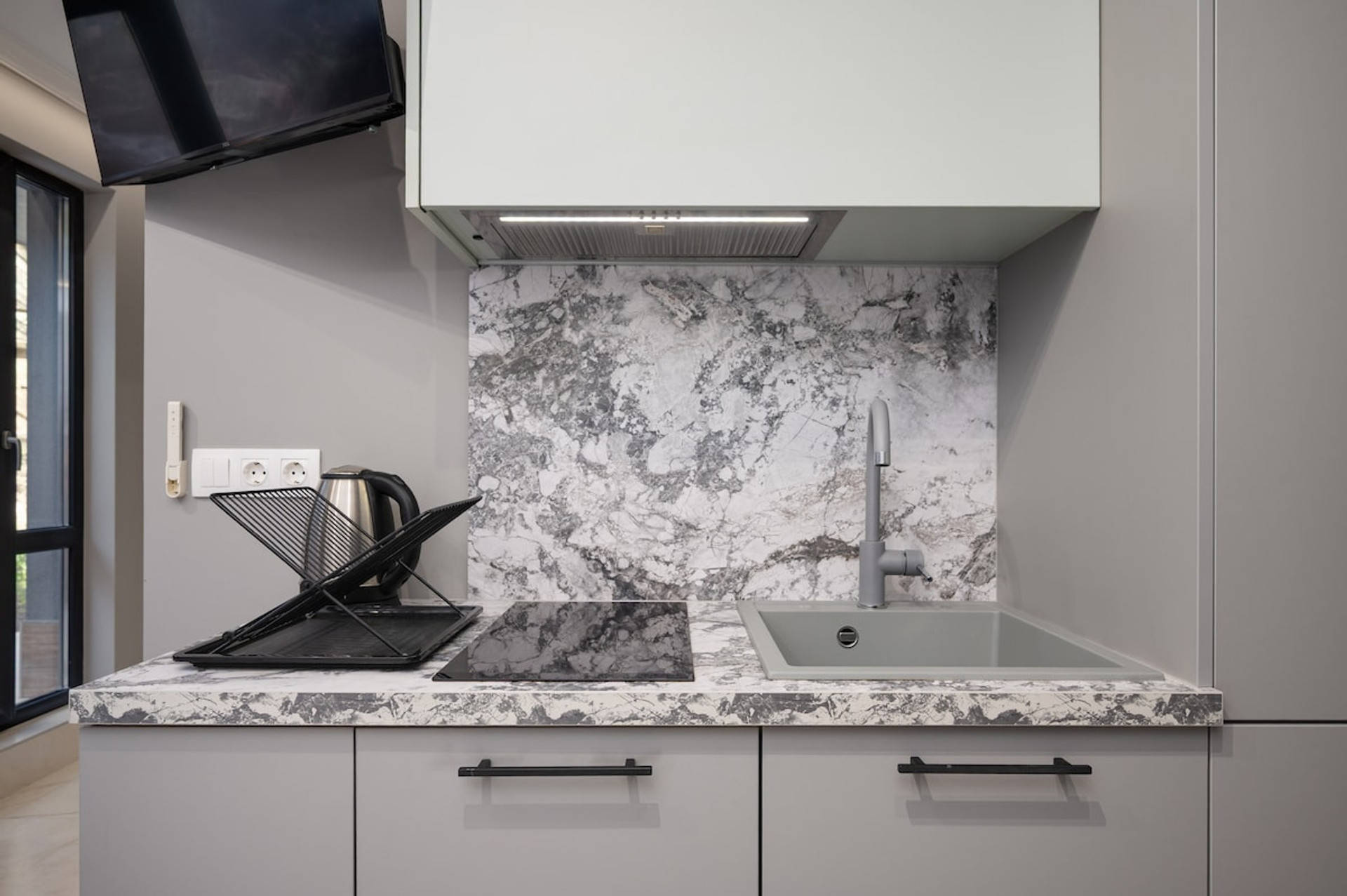 Prepare meals with ease in the fully equipped kitchenette featuring a modern stovetop and marble accents.