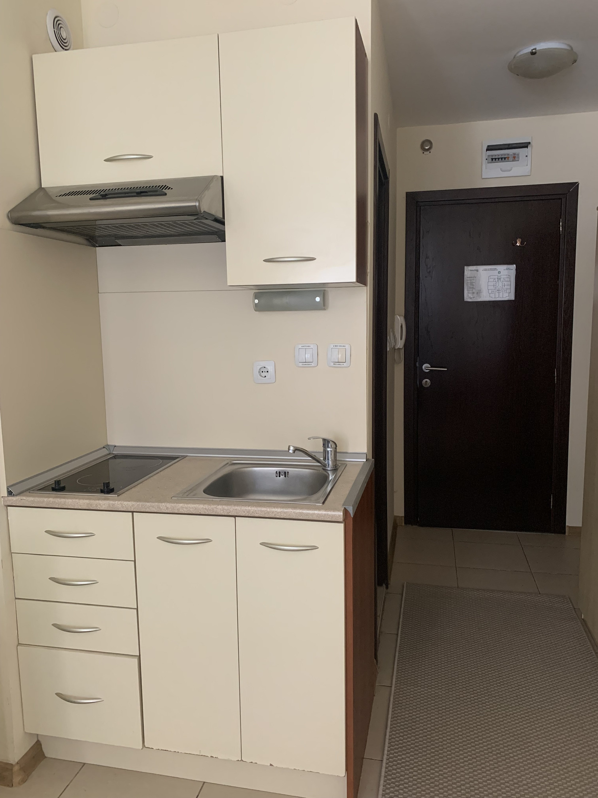Fully equipped kitchenette: cream cabinetry, stainless mini-fridge, sink and ample storage.