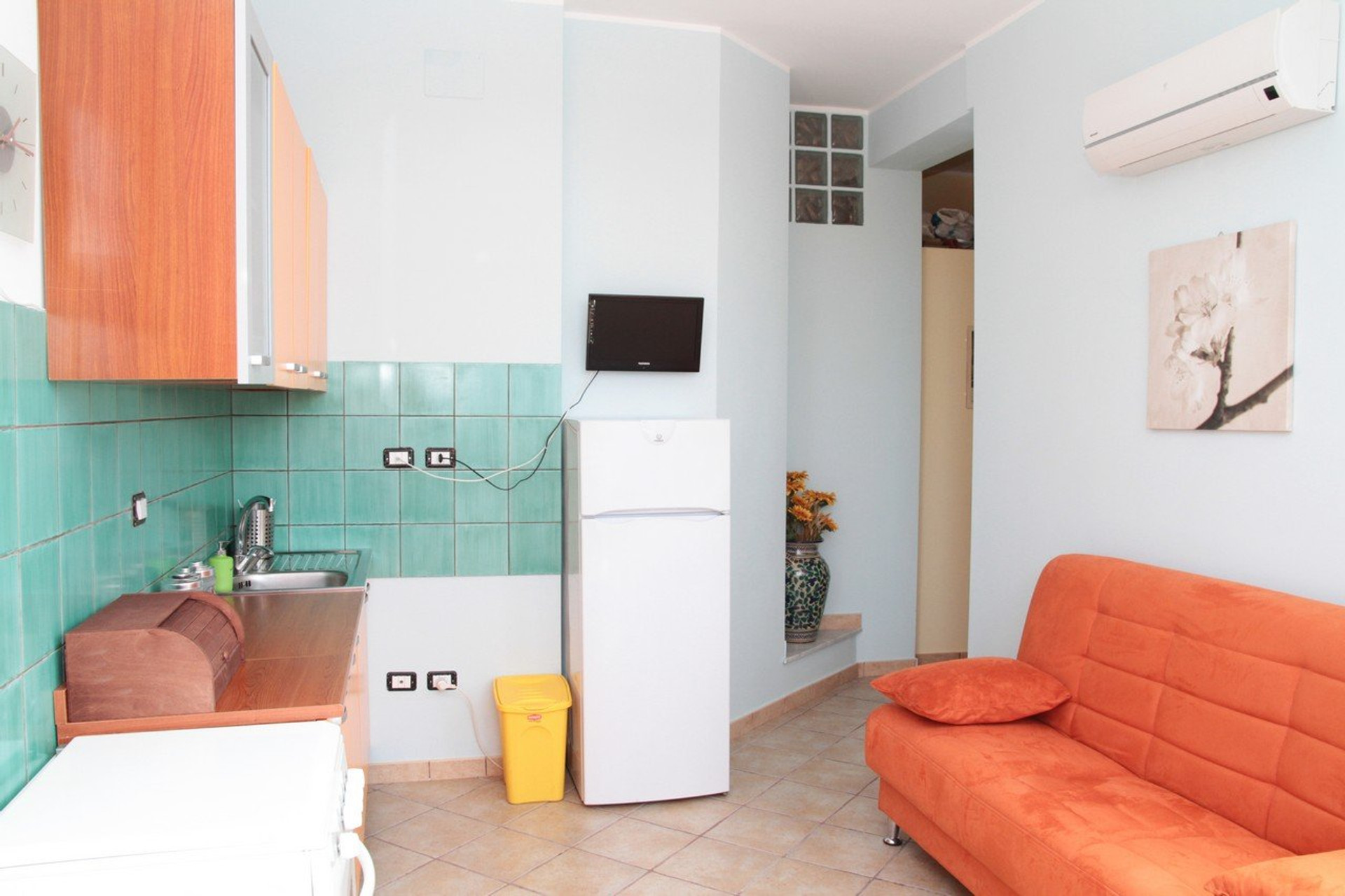 Living area with orange sofa, kitchenette