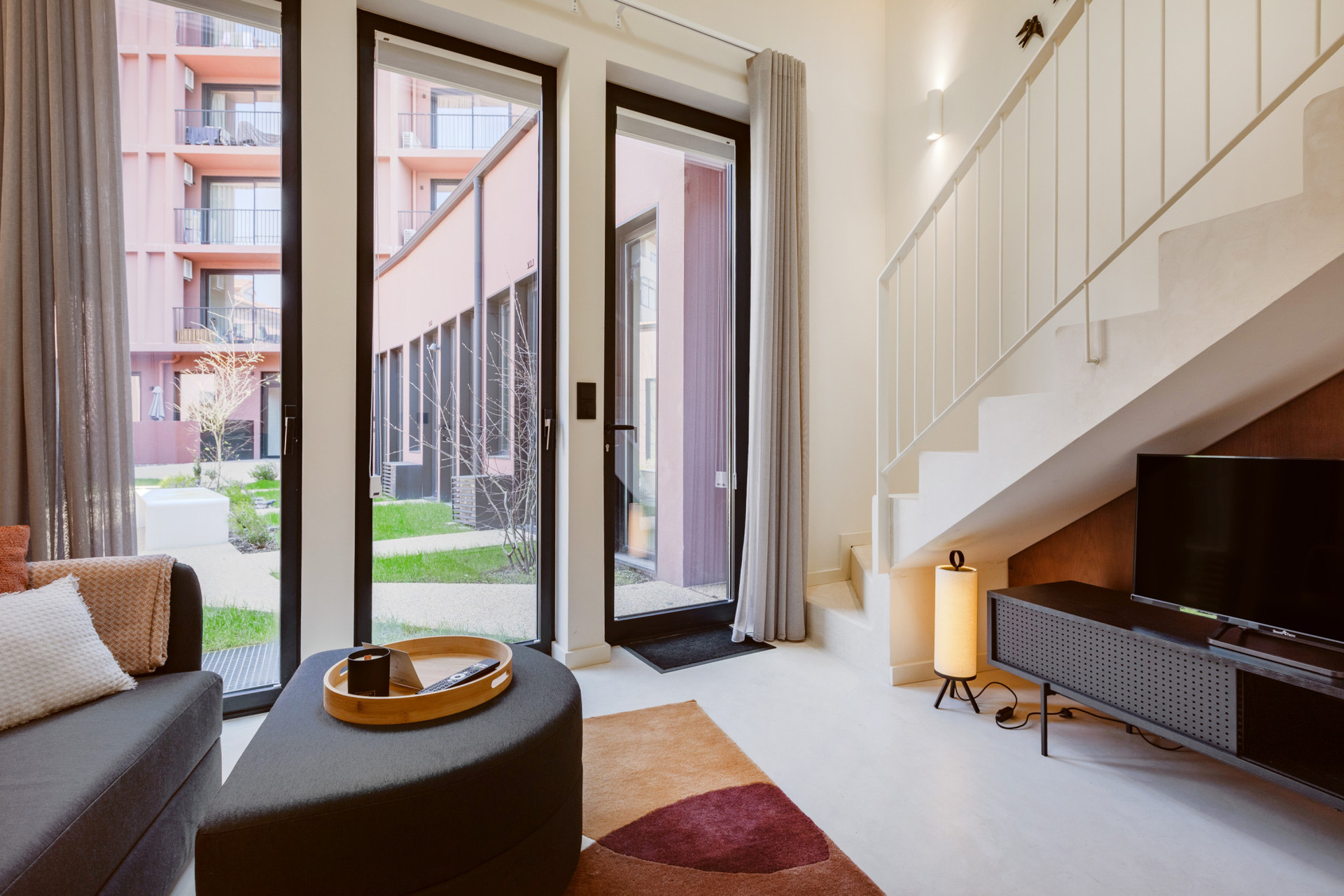 Living room with a two-seater sofa and Smart TV. Opens onto the building's private gardens.