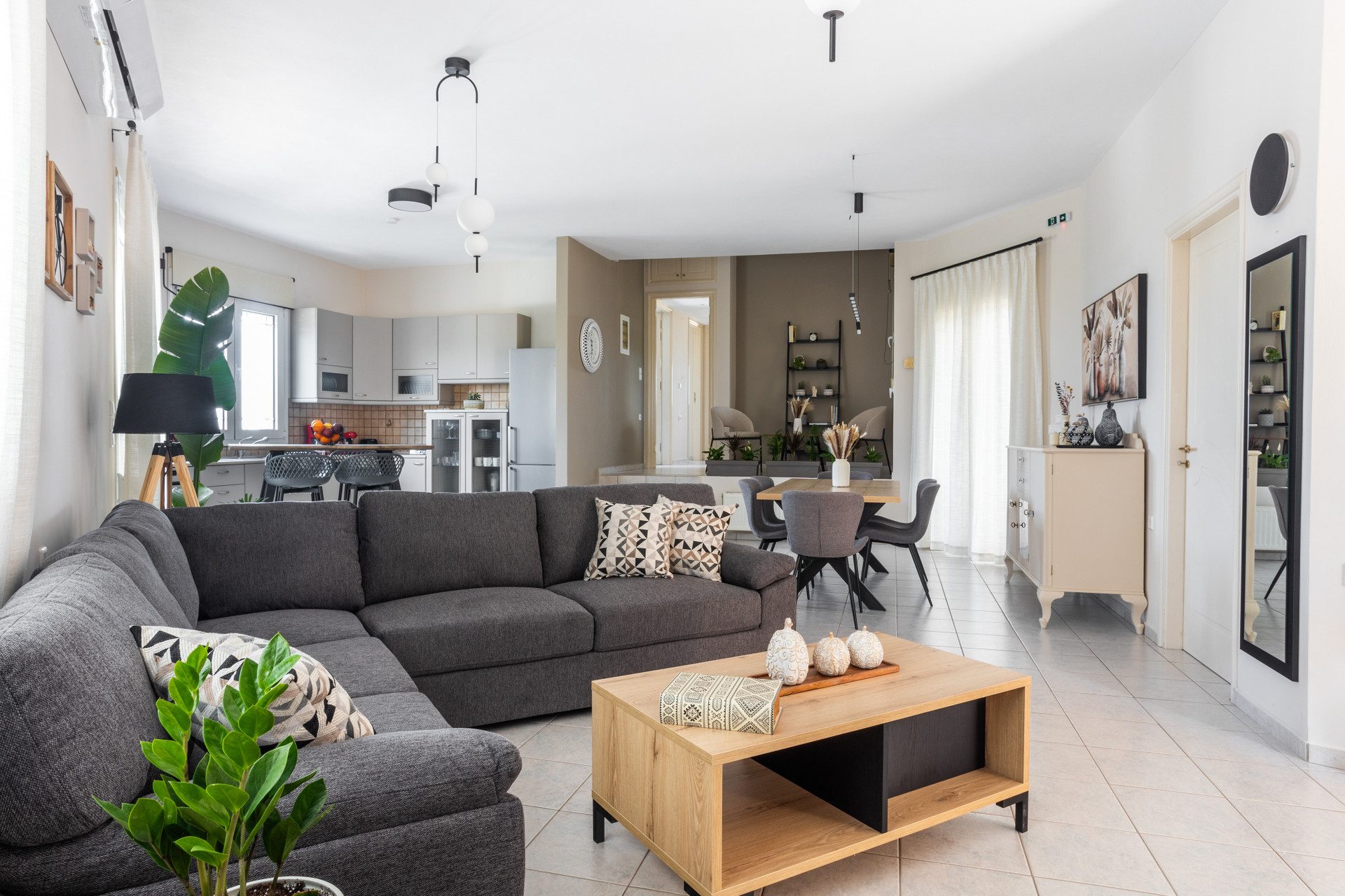 Inviting living space with large grey sectional sofa, wooden coffee table, and green plants