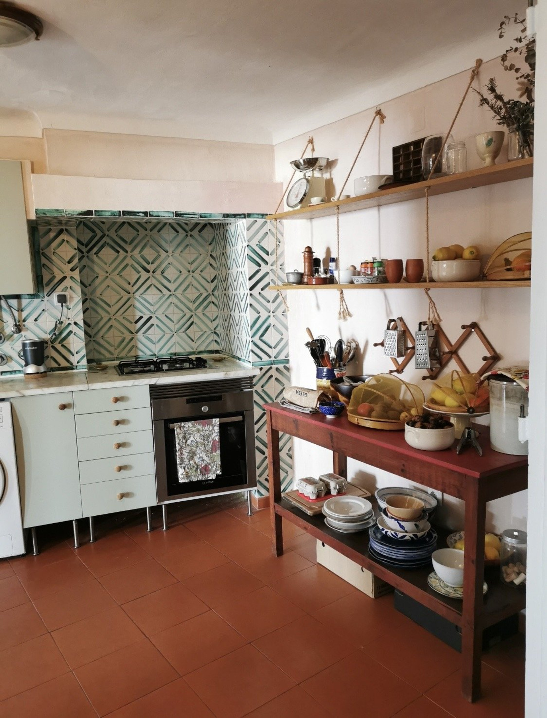 Kitchen with green tiles and shelves