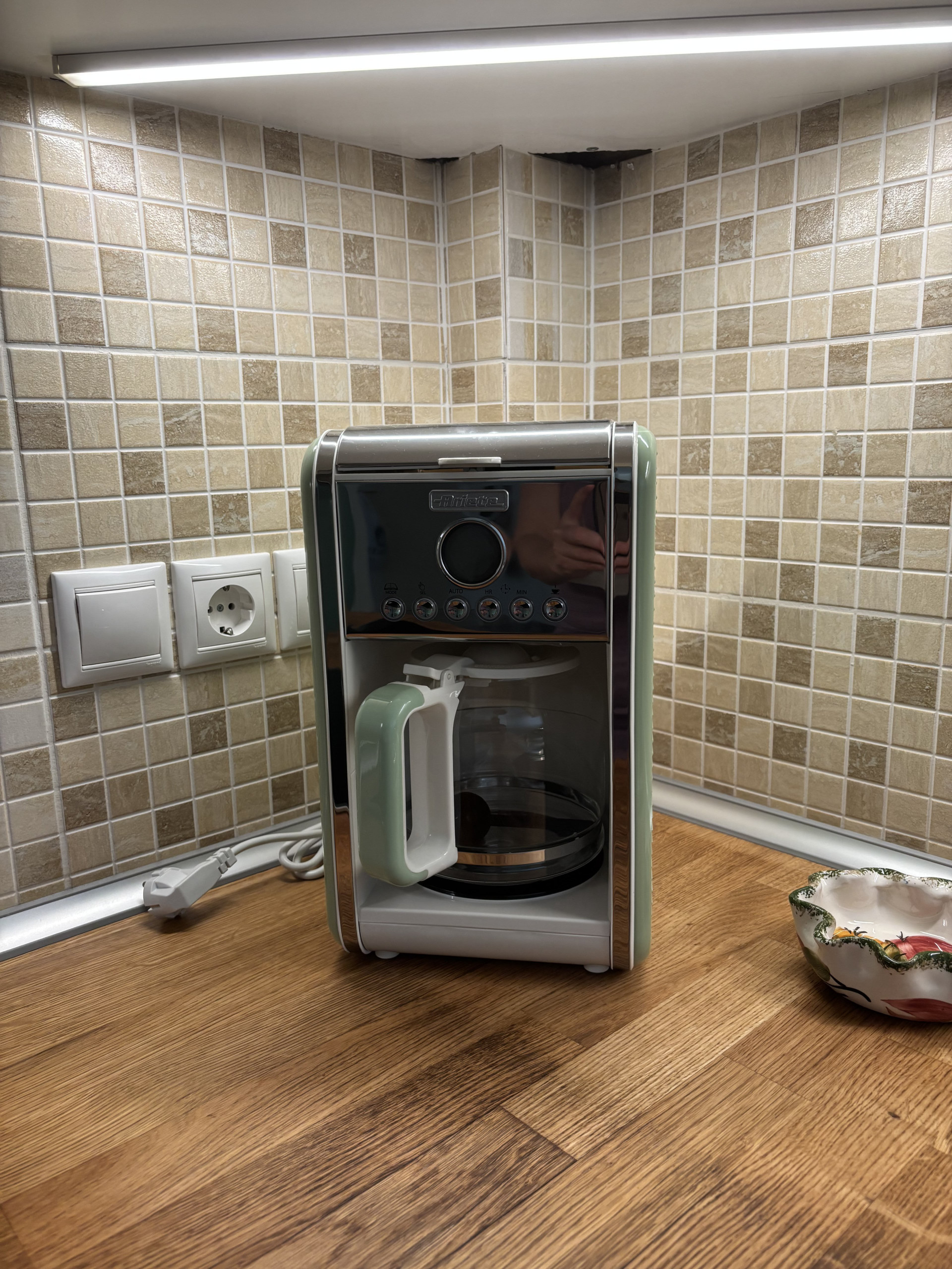 Start your mornings right with the retro-style drip coffee maker, neatly placed on the warm wooden countertop alongside classic tiled splashback