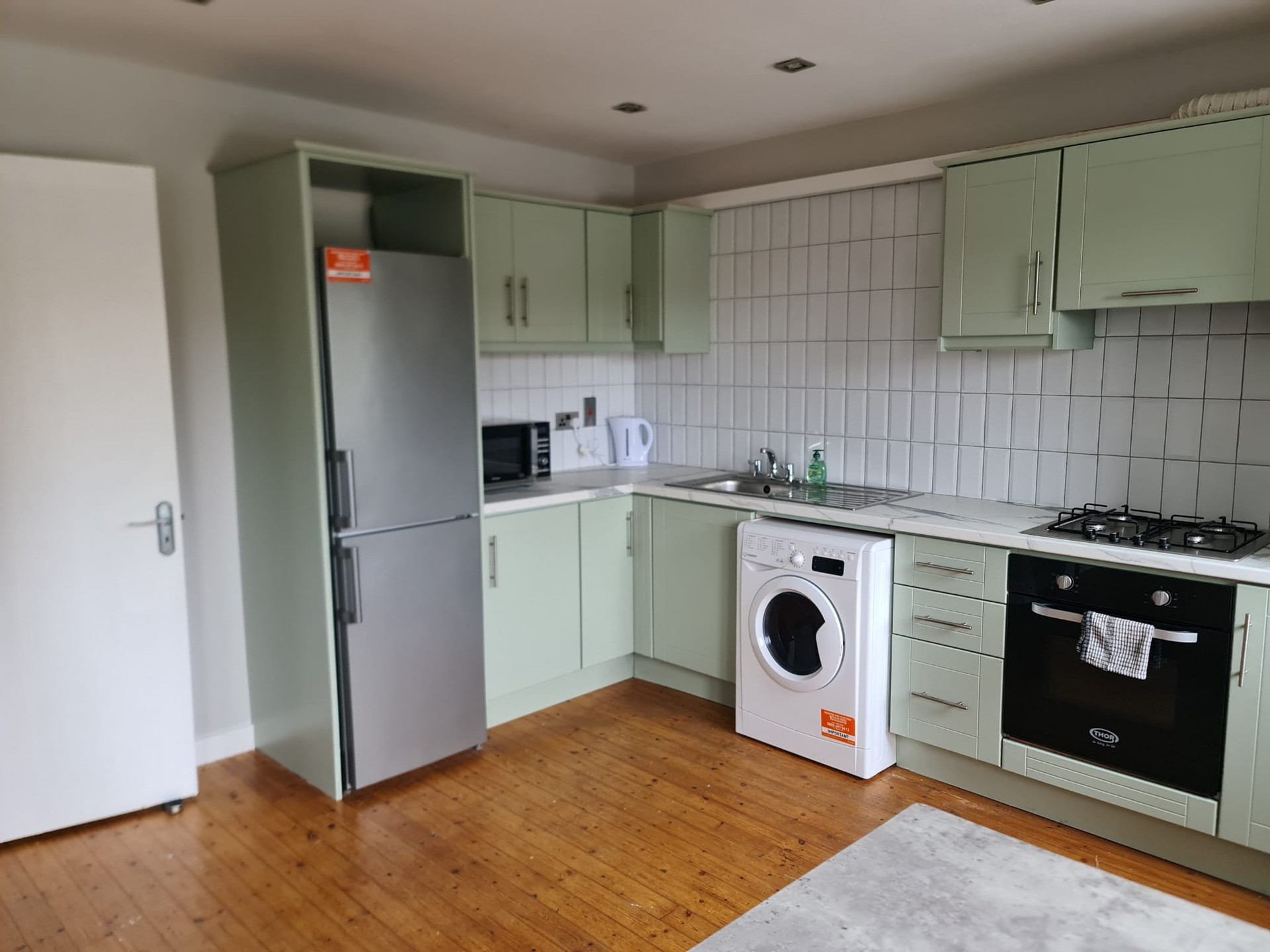 Green kitchen with appliances and washer