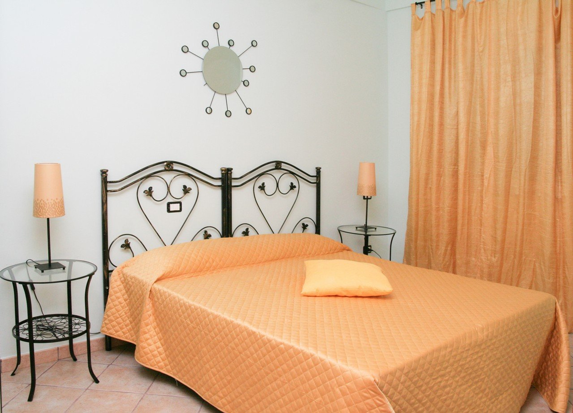Bedroom with orange bedspread, wrought-iron headboard