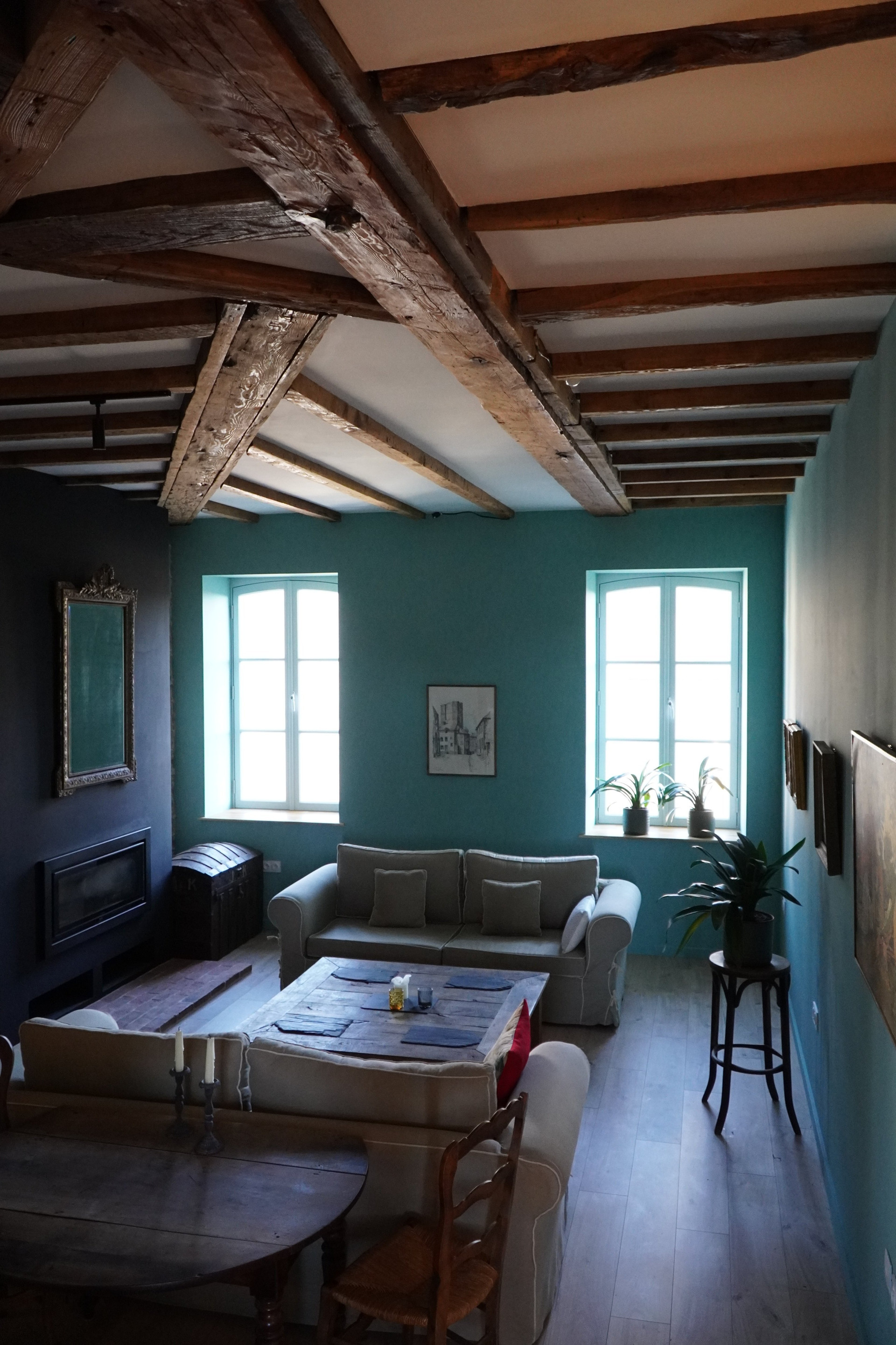 Stylish living space with timber beams, vintage touches, and soft light from tall windows. A calming base in medieval Saint-Yrieix-la-Perche—ideal for remote working.