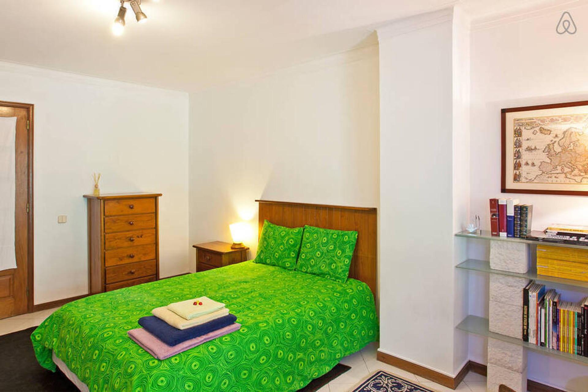Bedroom with green bedding and bookshelf