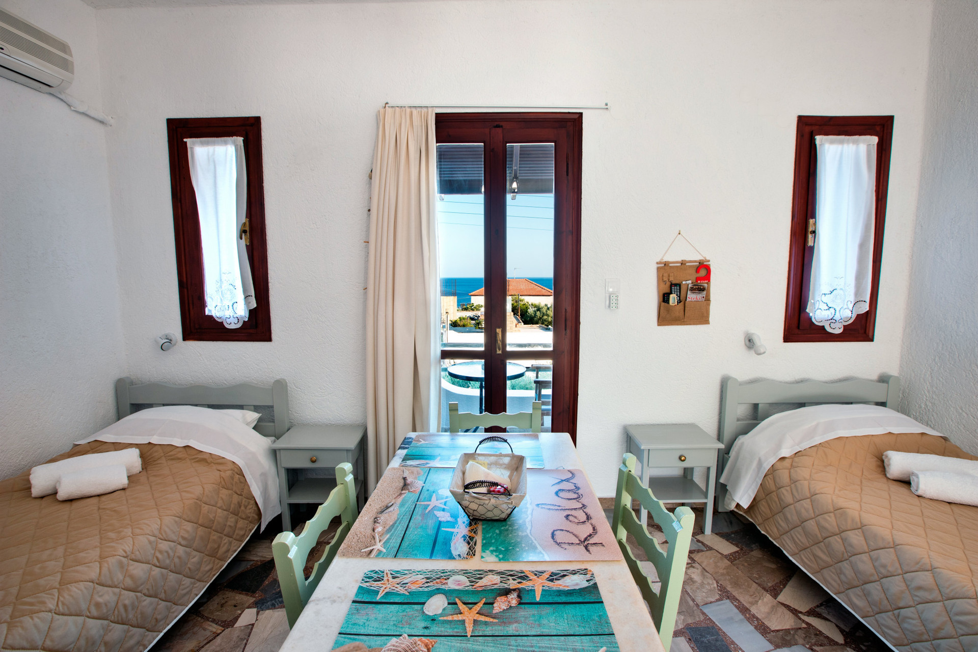 View of the living room with two single beds, table with chairs and entrance to balcony