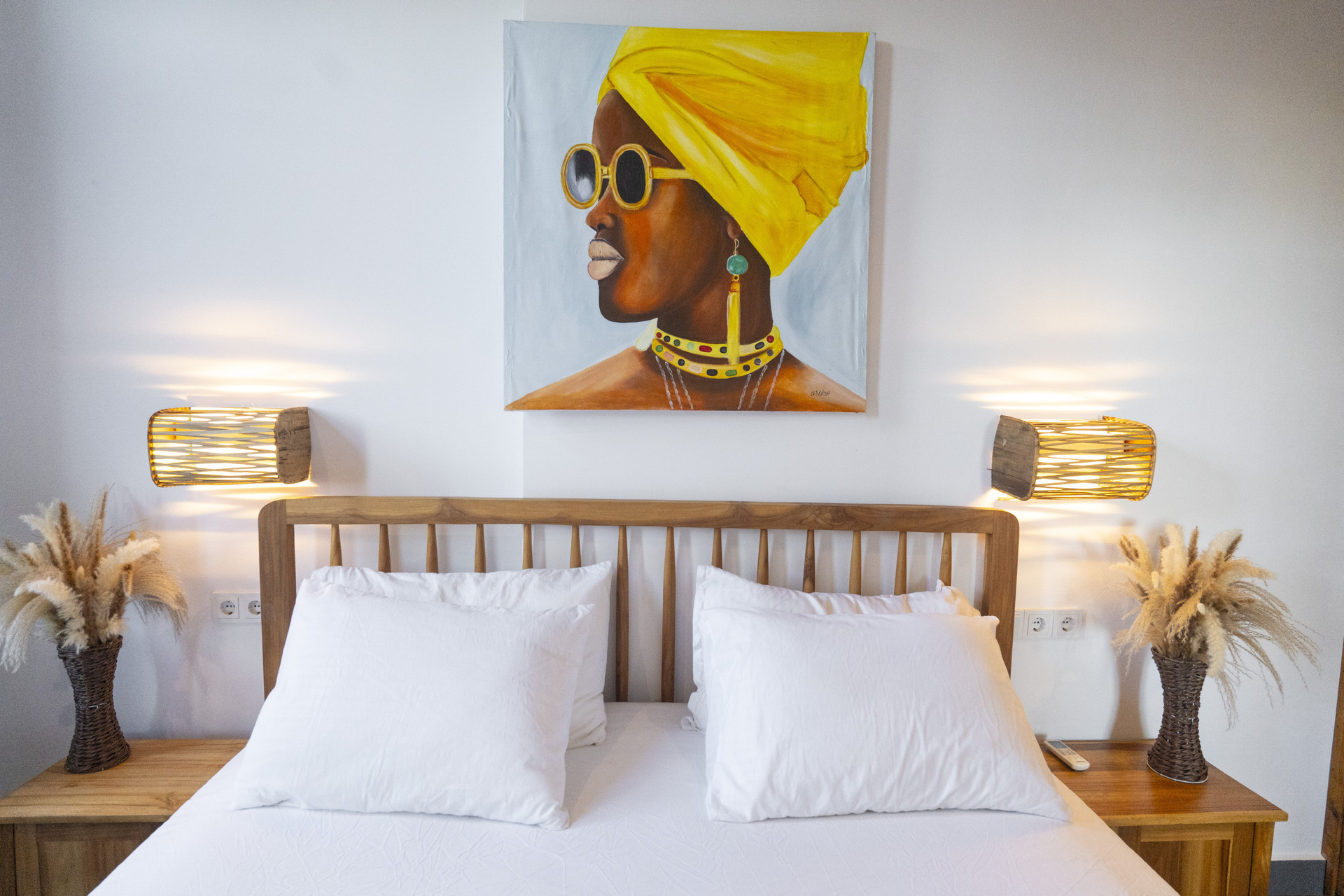 Bed with artwork and wooden lamps