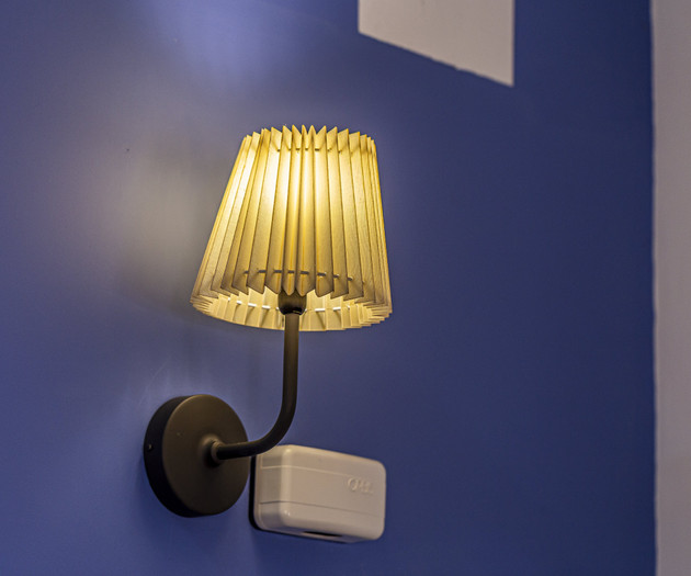 Pleated wall sconce on blue wall