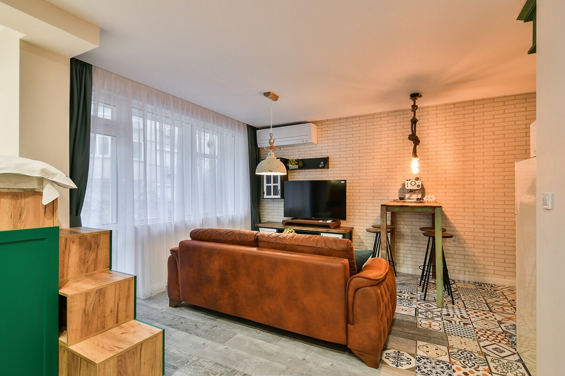 A beautifully designed lounge with plush seating, unique industrial lighting, and textured brick walls. The perfect place to relax, watch TV, or enjoy a cozy evening indoors.