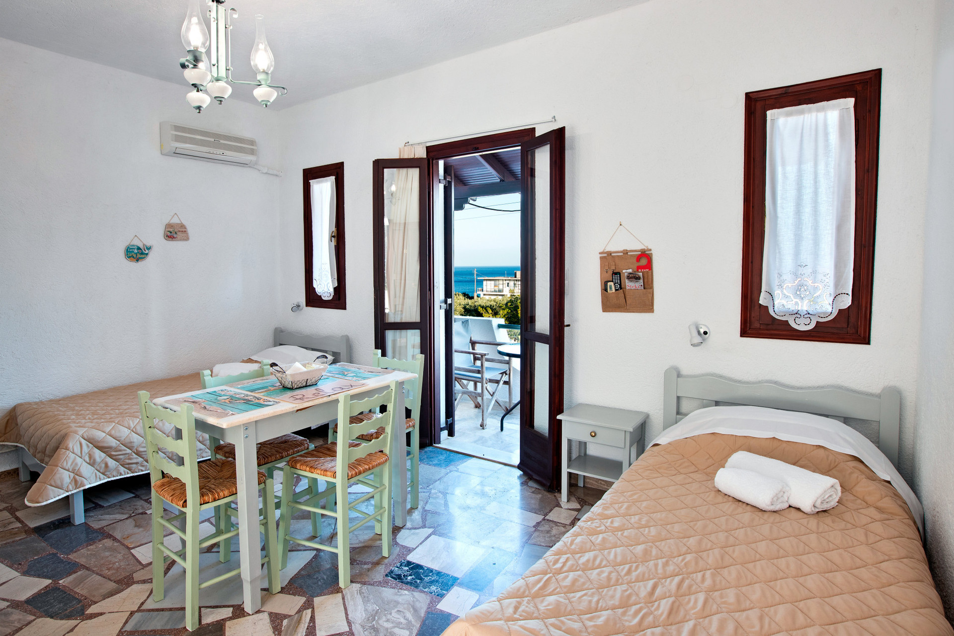 View of the living room with two single beds, table with chairs and entrance to balcony